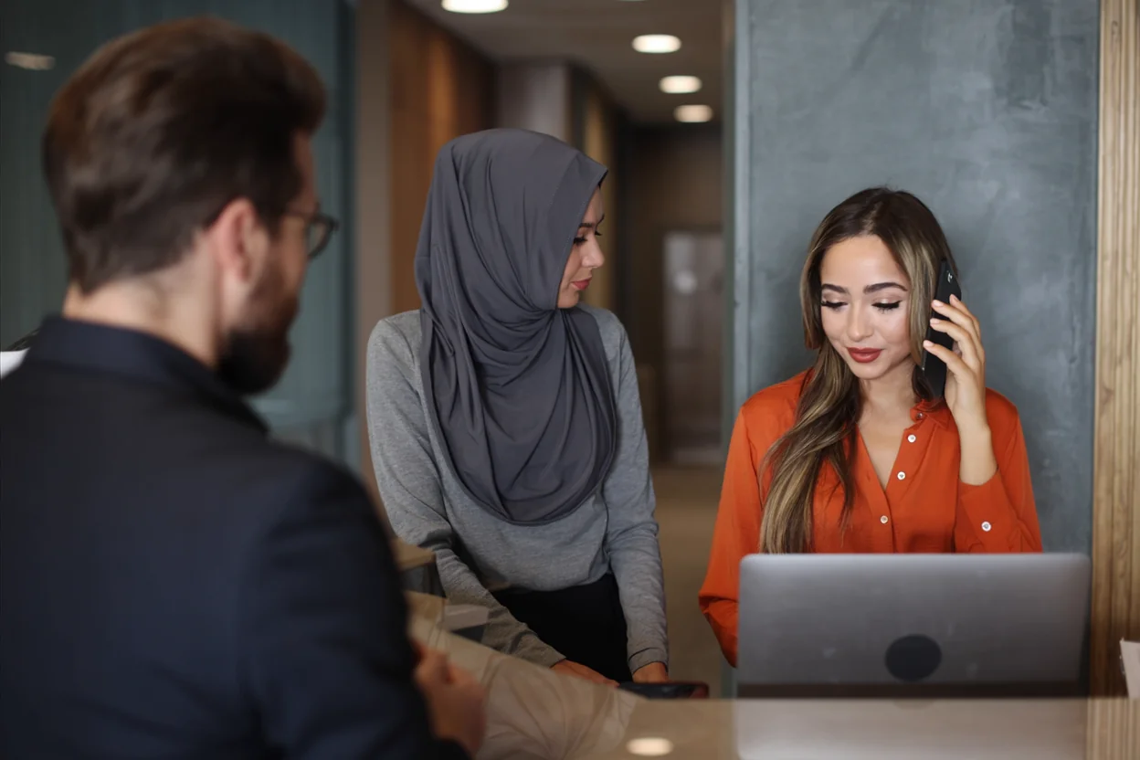 Two members of the Akouri Law front office team assisting a client at the reception desk